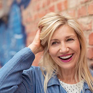 a woman running her fingers through her hair with a joyful smile